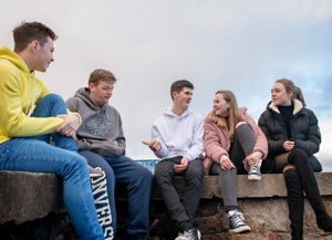 Five young people sitting on a wall