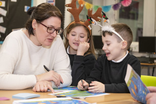 Adult sitting at a desk with two children