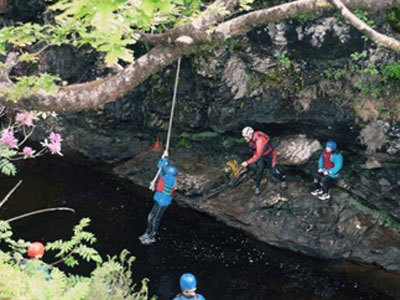 Photo of children playing on a rope swing over a stream