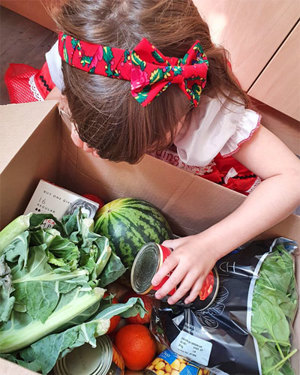 Girl looking at food items in cardboard box