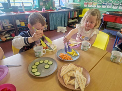 Photo of 2 children eating vegetables